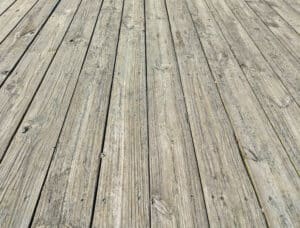 Several long pressure treated boards of a deck weathered with age.