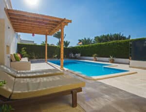 Luxury villa show home in tropical summer holiday resort with outdoor swimming pool and sun chairs