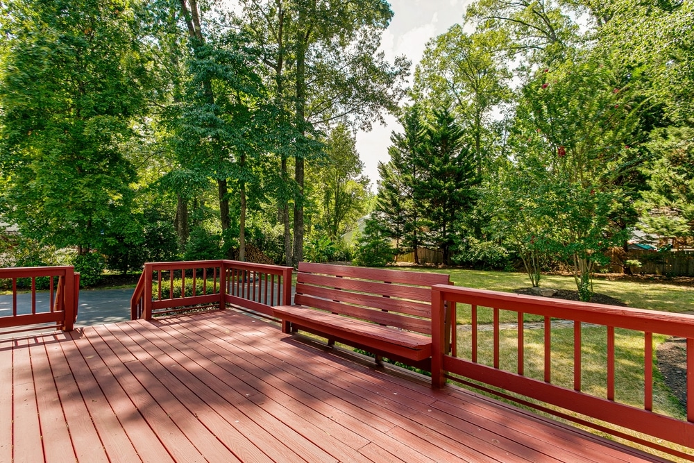 Why You Should Consider Adding Built-In Benches to Your Deck Design 3 Red Deck In A Backyard Surrounded By Lush Green Trees And Bushes with Built in Bench